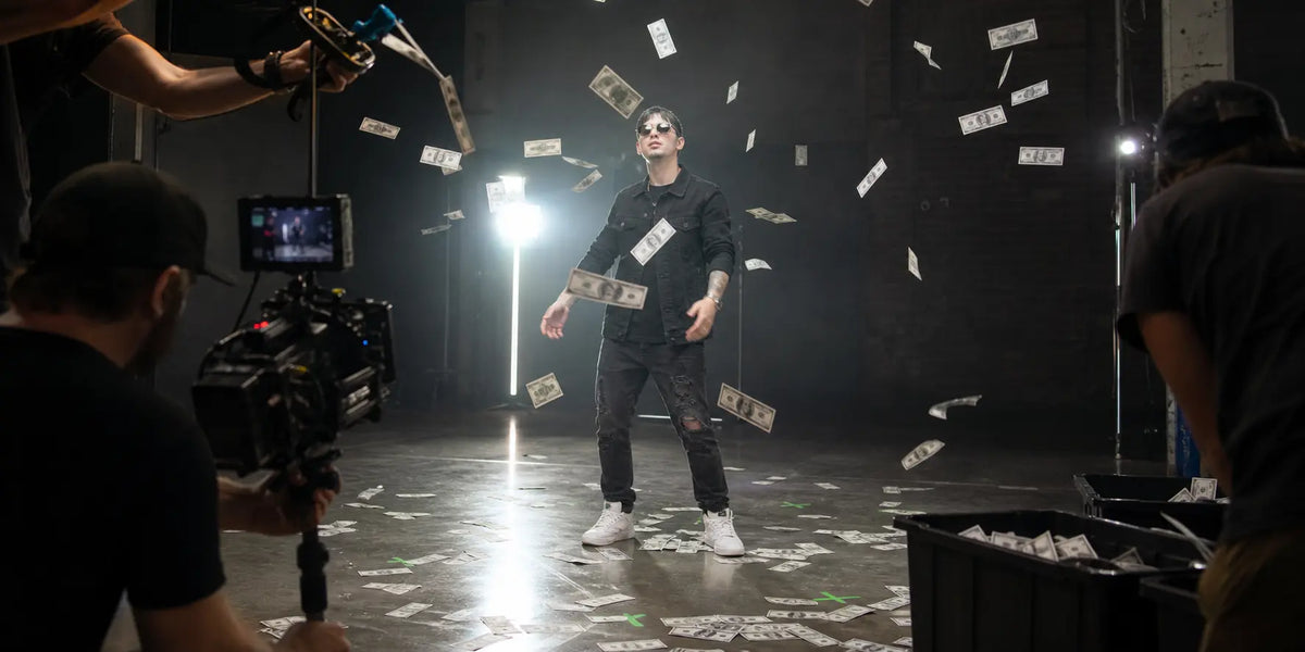 Performer stands beneath falling prop bills during a controlled music-video shoot.