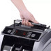 Hand lifting the money counter by its top carrying handle