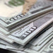 Close-up of overlapping RealAged® $100 prop money bills showing aged paper and printed detail